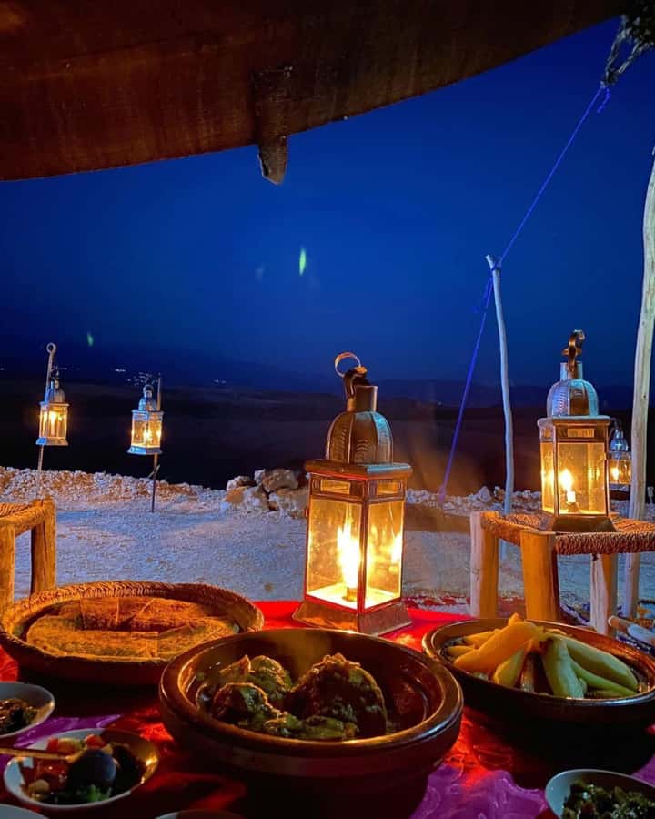 A lantern-lit table for two at the edge of the Agafay desert at dusk
